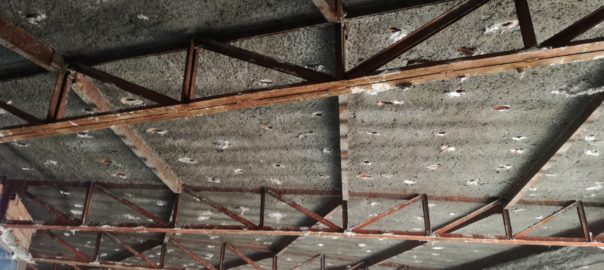 Struttura tetto con travi metalliche arrugginite.