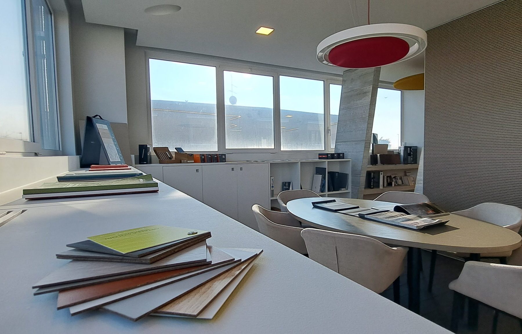 Ufficio moderno, illuminato, con tavolo riunioni e campioni.