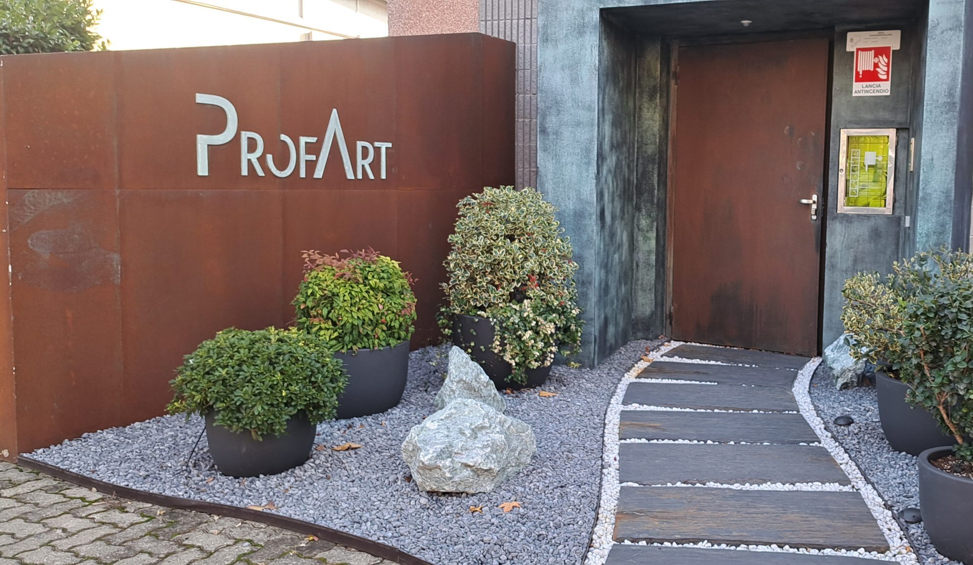 Ingresso azienda ProfArt con piante e percorso decorativo.