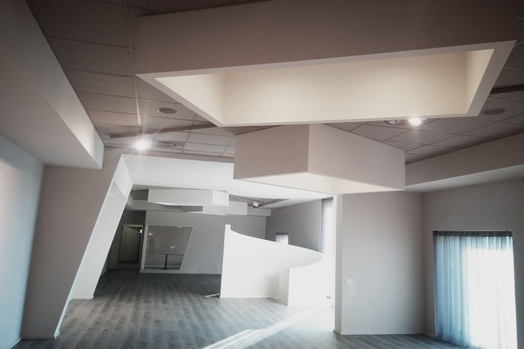 Interno moderno con soffitto geometrico e luci incassate.