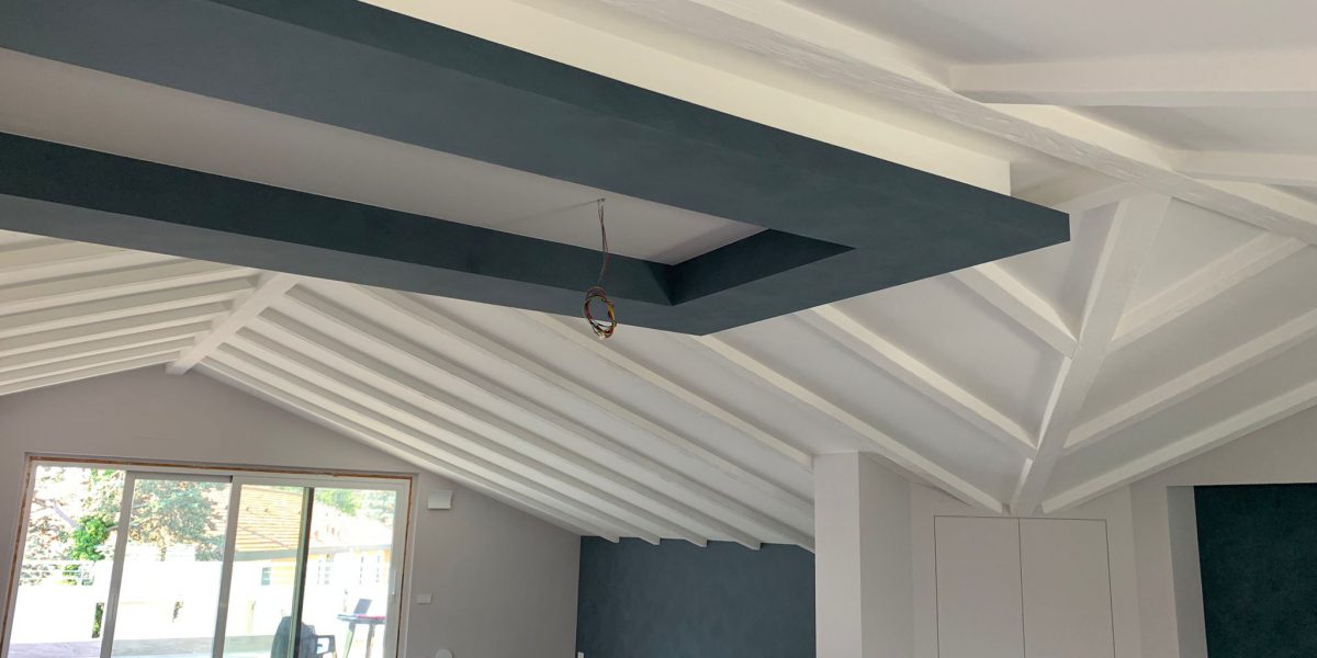 Soffitto mansardato con travi bianche in interni moderni.