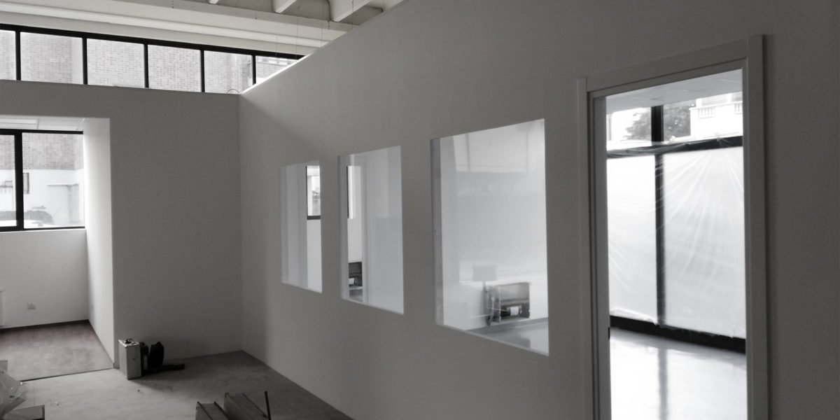 Interno moderno, pareti bianche, finestre squadrate, ufficio vuoto.