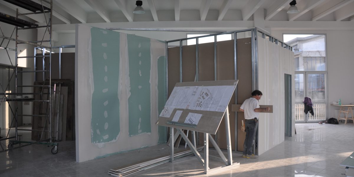 Uomo in cantiere con progetti architettonici.