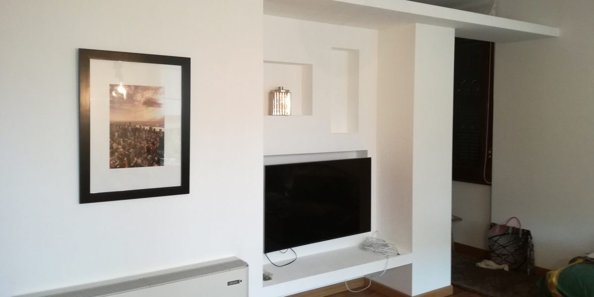 Soggiorno moderno con TV e quadro decorativo.